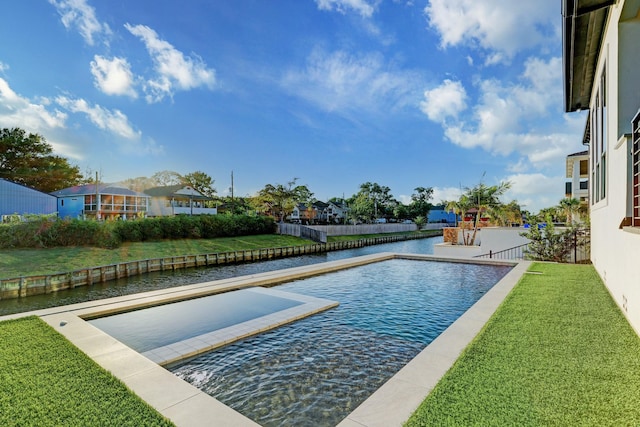 view of swimming pool with a lawn and a water view