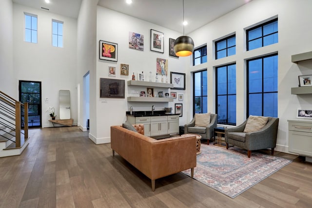 living room featuring a high ceiling, plenty of natural light, dark wood-type flooring, and bar area