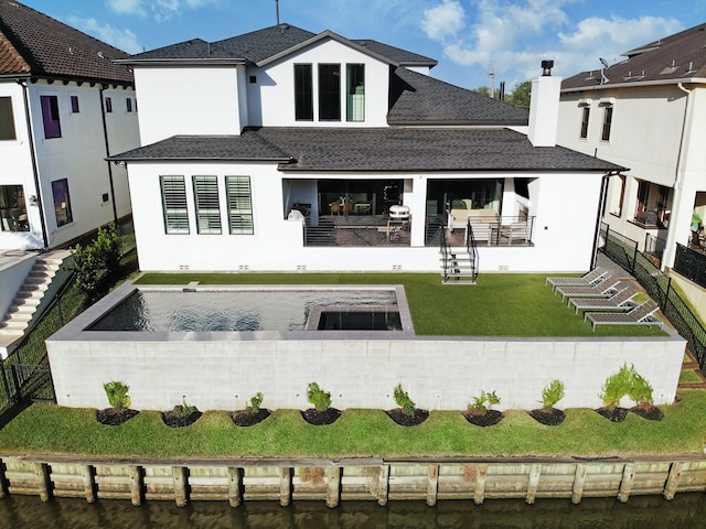 rear view of property featuring a water view and a lawn