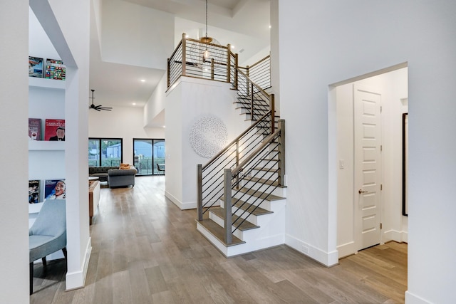 stairs featuring hardwood / wood-style flooring, a towering ceiling, and ceiling fan