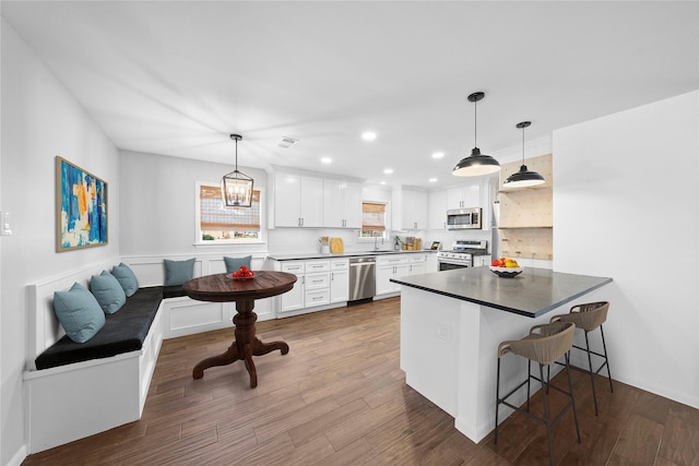 kitchen with appliances with stainless steel finishes, a breakfast bar, breakfast area, white cabinets, and kitchen peninsula