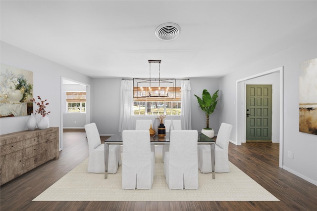 dining room with dark hardwood / wood-style flooring and a notable chandelier