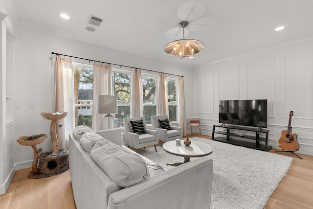 living room with ornamental molding, light wood-type flooring, and a chandelier