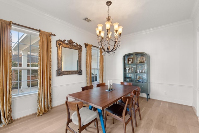 dining area with crown molding, a notable chandelier, and light wood-type flooring