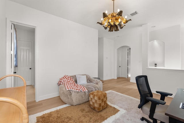 home office with an inviting chandelier and light hardwood / wood-style flooring