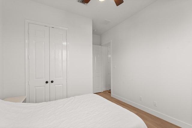 bedroom with ceiling fan, light hardwood / wood-style floors, and a closet