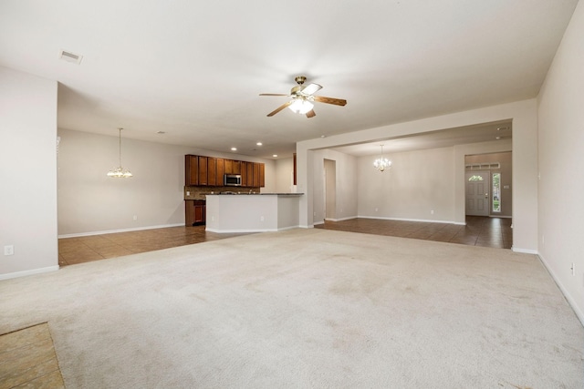 unfurnished living room with ceiling fan with notable chandelier and carpet flooring