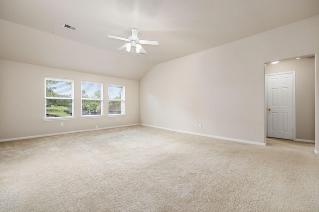 empty room featuring vaulted ceiling, light colored carpet, and ceiling fan