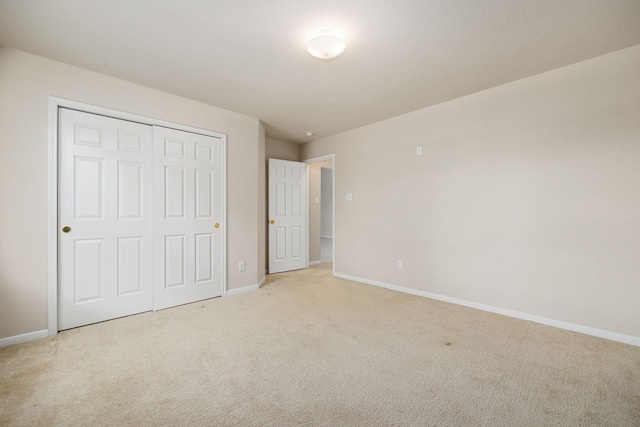 unfurnished bedroom with light carpet and a closet