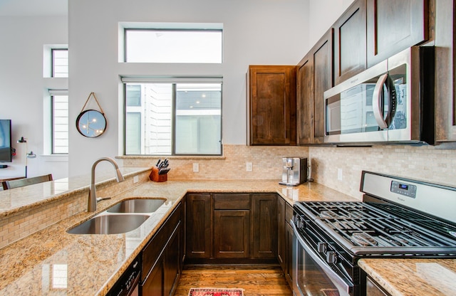 kitchen featuring sink, light hardwood / wood-style flooring, appliances with stainless steel finishes, backsplash, and light stone countertops