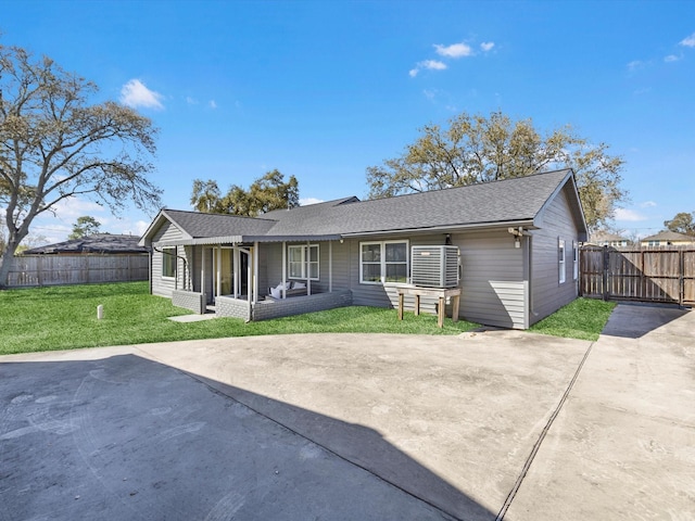 rear view of property featuring a shingled roof, fence, a lawn, and concrete driveway