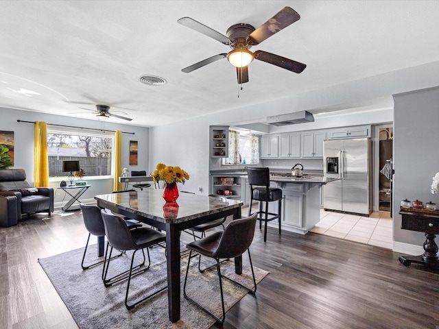 dining room with light wood-style floors, baseboards, visible vents, and a ceiling fan