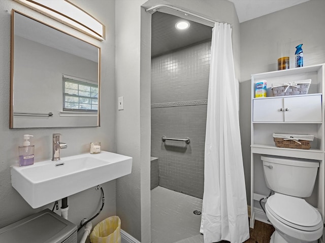 bathroom featuring toilet, baseboards, and tiled shower