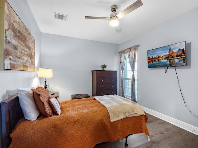 bedroom featuring a ceiling fan, visible vents, baseboards, and wood finished floors