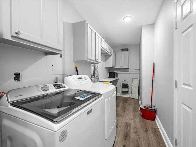 laundry area featuring cabinet space, baseboards, washer and clothes dryer, and wood finished floors