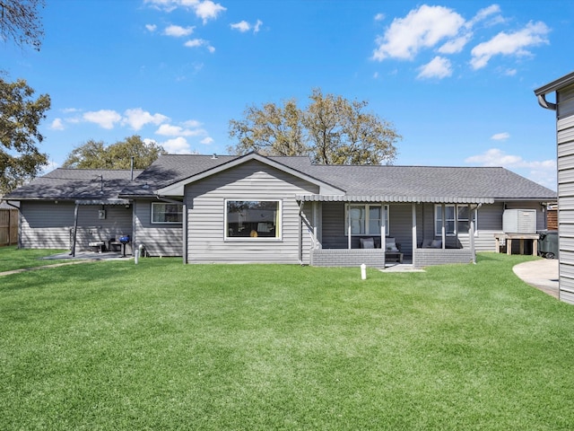 rear view of property featuring a patio, a lawn, and roof with shingles