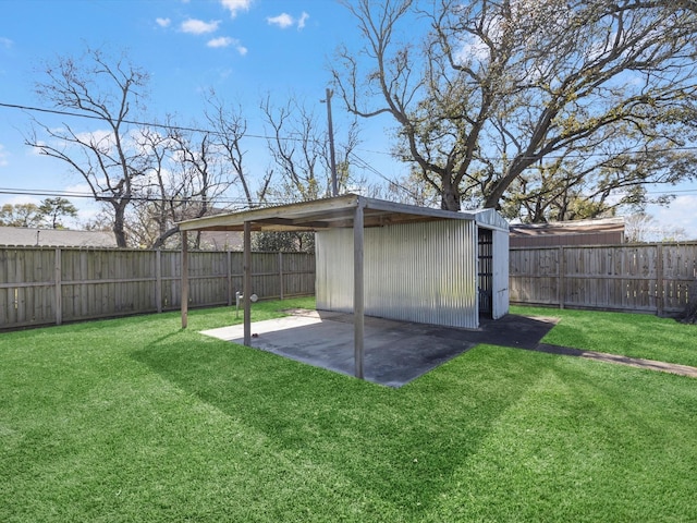 view of yard featuring a carport, an outdoor structure, and a fenced backyard