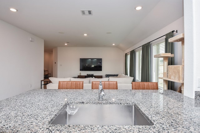 kitchen with light stone counters, sink, and lofted ceiling