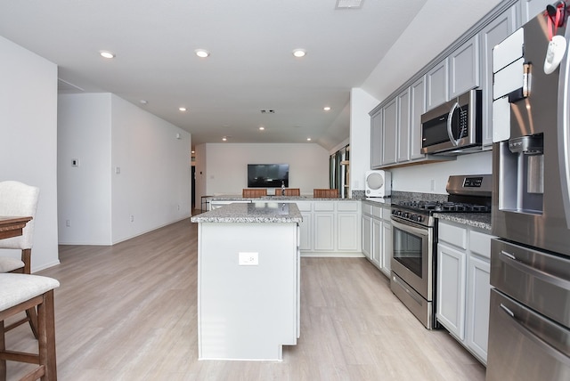 kitchen featuring gray cabinetry, light stone counters, light wood-type flooring, appliances with stainless steel finishes, and kitchen peninsula