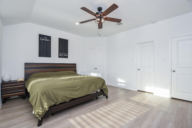 bedroom with hardwood / wood-style flooring, vaulted ceiling, ceiling fan, and a closet