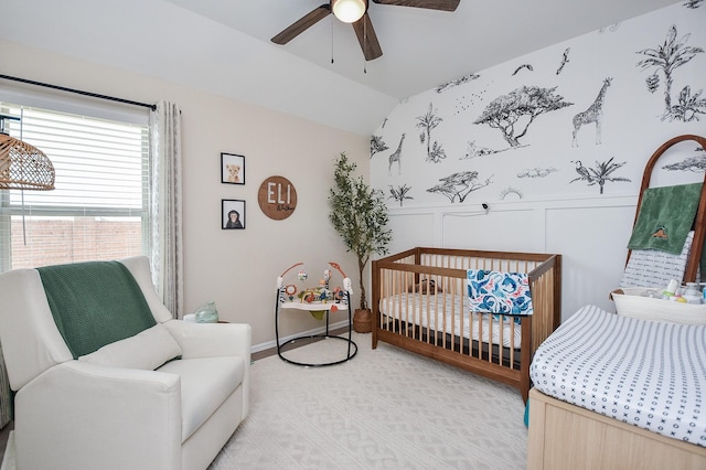 carpeted bedroom with vaulted ceiling, a nursery area, and ceiling fan