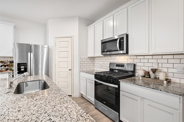 kitchen with light stone counters, stainless steel appliances, and white cabinets