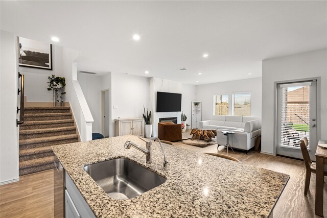 kitchen with sink, light hardwood / wood-style flooring, and light stone countertops