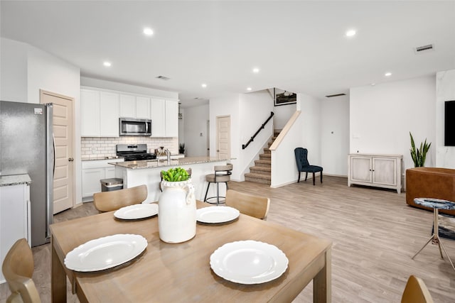 dining space with sink and light hardwood / wood-style floors