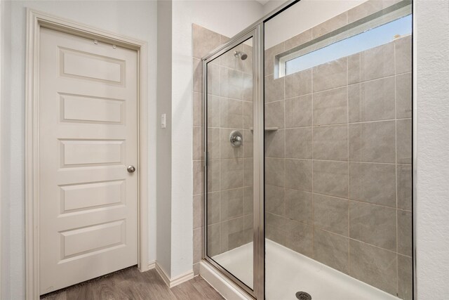 bathroom with a shower with shower door and hardwood / wood-style floors