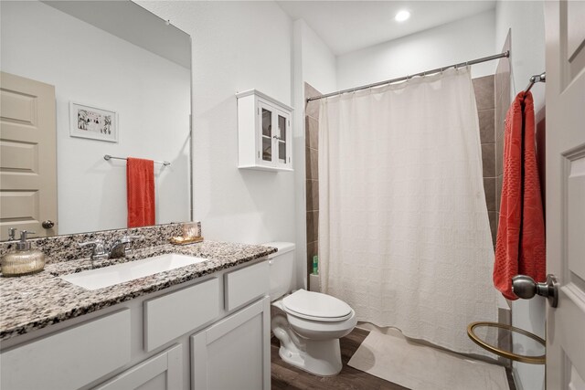 bathroom featuring hardwood / wood-style flooring, vanity, a shower with shower curtain, and toilet