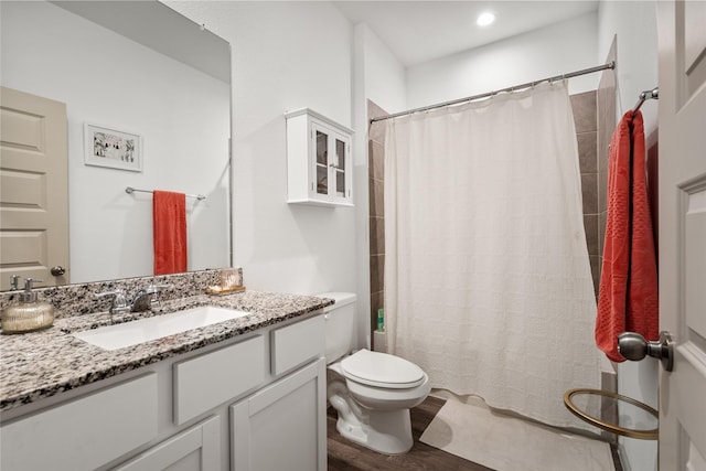 bathroom with toilet, curtained shower, wood finished floors, and vanity