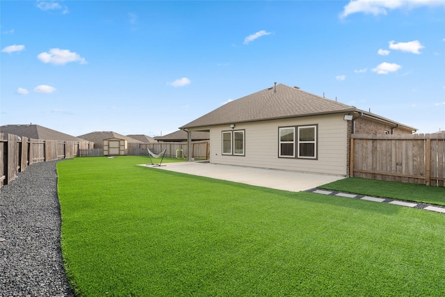 back of house with a shingled roof, a patio area, a lawn, and a fenced backyard