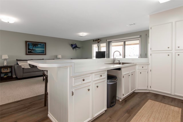 kitchen featuring sink, a breakfast bar area, dark hardwood / wood-style floors, white cabinets, and kitchen peninsula