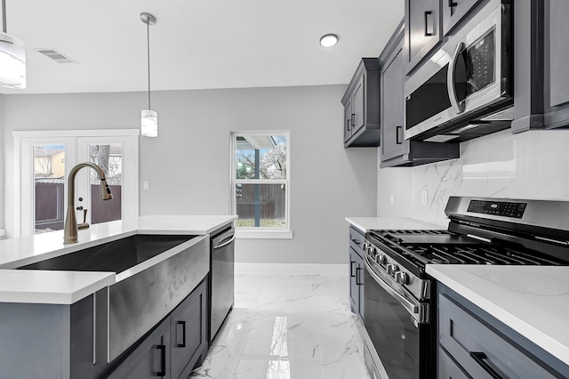 kitchen featuring sink, gray cabinetry, appliances with stainless steel finishes, pendant lighting, and decorative backsplash