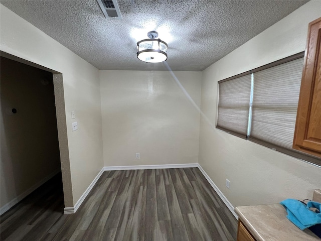 unfurnished dining area with dark hardwood / wood-style floors and a textured ceiling