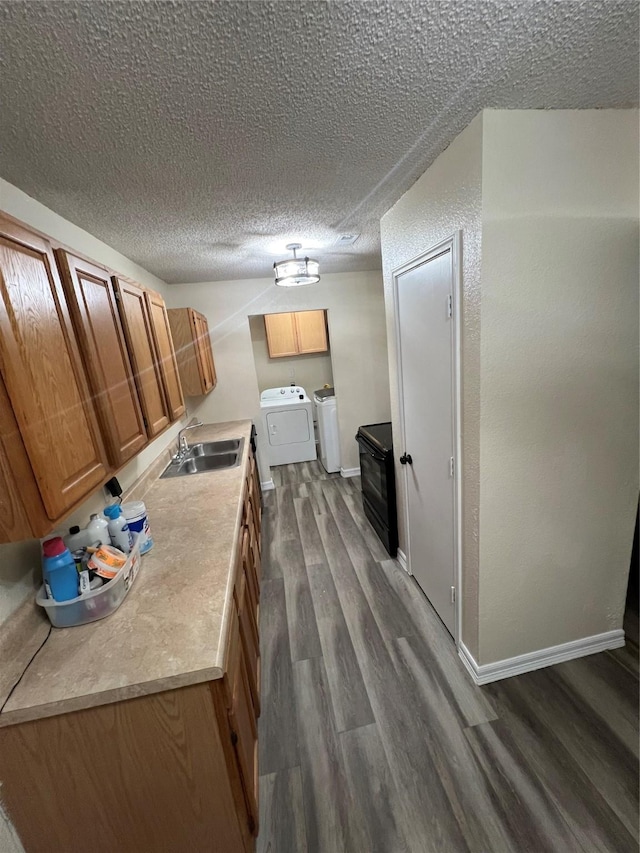 kitchen with dark wood-type flooring, independent washer and dryer, sink, and a textured ceiling