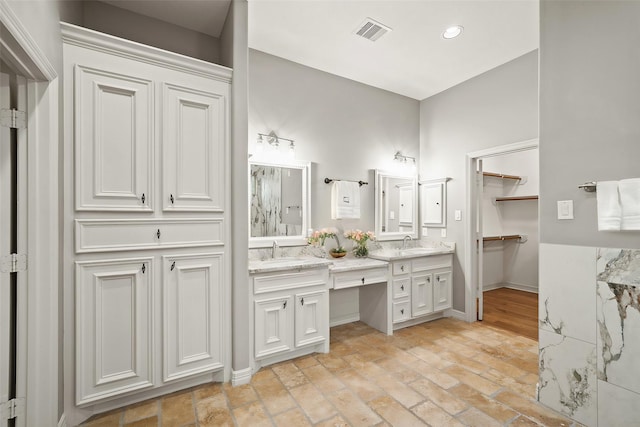 bathroom featuring brick flooring, vanity, baseboards, and recessed lighting