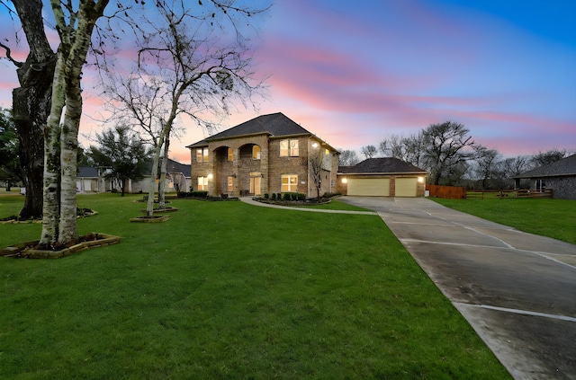 french country style house with brick siding, an attached garage, a front lawn, an outbuilding, and driveway