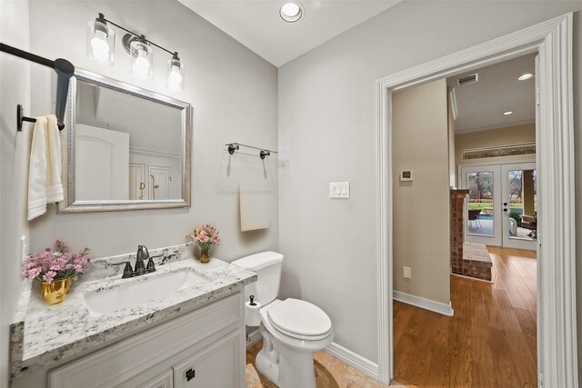 bathroom featuring toilet, vanity, wood finished floors, baseboards, and recessed lighting