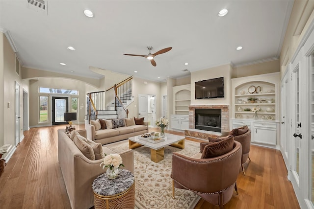 living room with ceiling fan, ornamental molding, built in features, and light hardwood / wood-style flooring