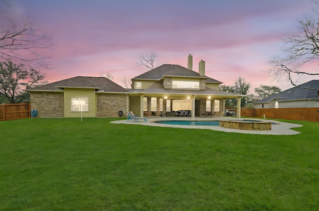 back house at dusk with a pool with hot tub, a patio area, and a lawn