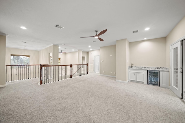 empty room with wine cooler, a ceiling fan, recessed lighting, light colored carpet, and bar area