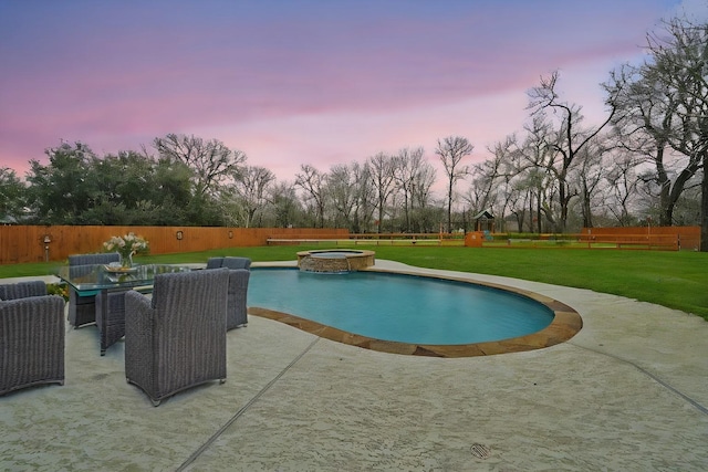 pool at dusk with an in ground hot tub, a patio area, and a lawn