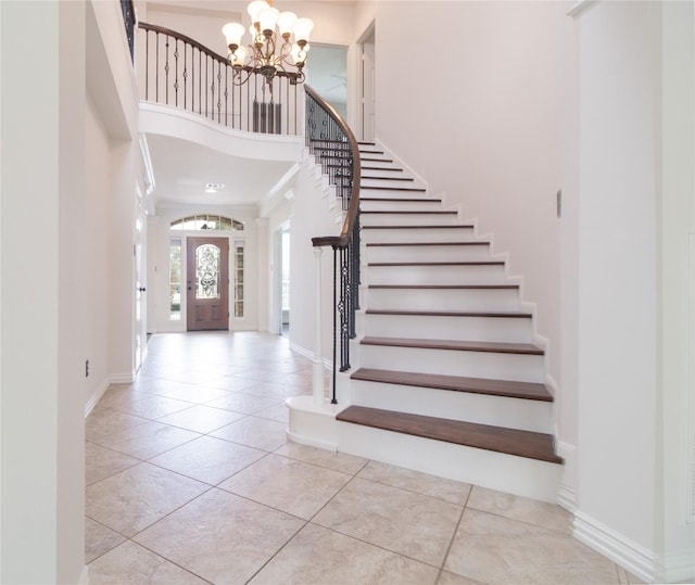 entrance foyer featuring a towering ceiling, a chandelier, and light tile patterned floors