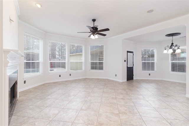 tiled spare room with ornamental molding, a wealth of natural light, and ceiling fan with notable chandelier