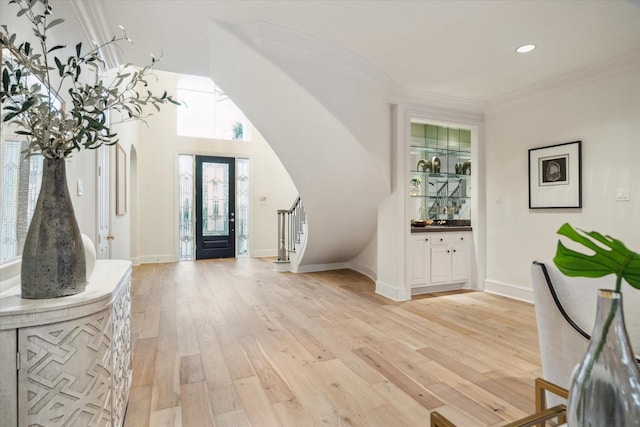 foyer entrance with ornamental molding and light hardwood / wood-style floors