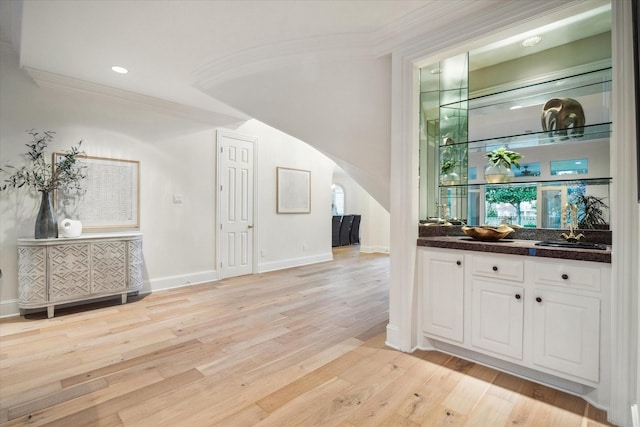 bar featuring white cabinetry, ornamental molding, sink, and light hardwood / wood-style floors