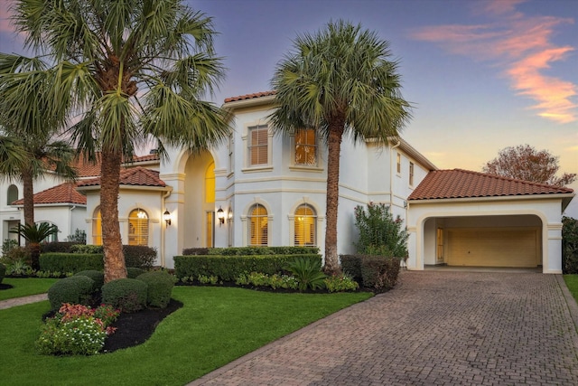 mediterranean / spanish-style home featuring a garage and a lawn