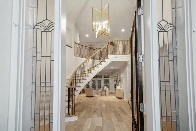 entrance foyer featuring a towering ceiling, a notable chandelier, and light wood-type flooring