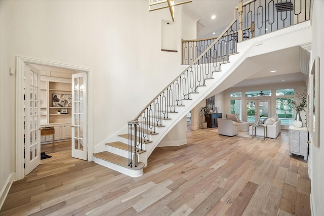 staircase featuring a high ceiling, wood-type flooring, and french doors